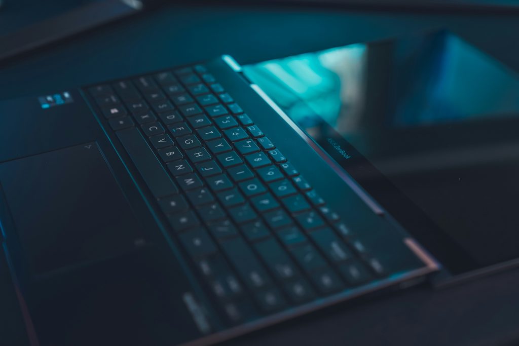 Close-up of a laptop keyboard lit in turquoise