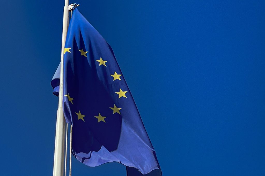 Un drapeau européen flotte sur son mât, se détachant sur un ciel bleu profond
