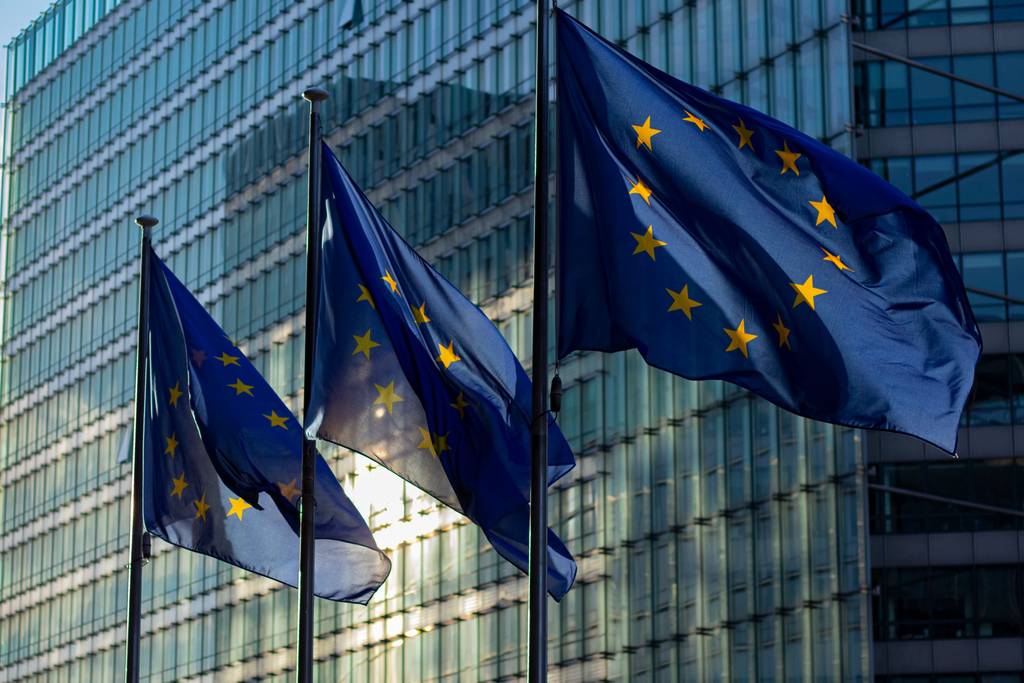 Trois drapeaux européens flottent devant la façade vitrée d’un immeuble de bureaux