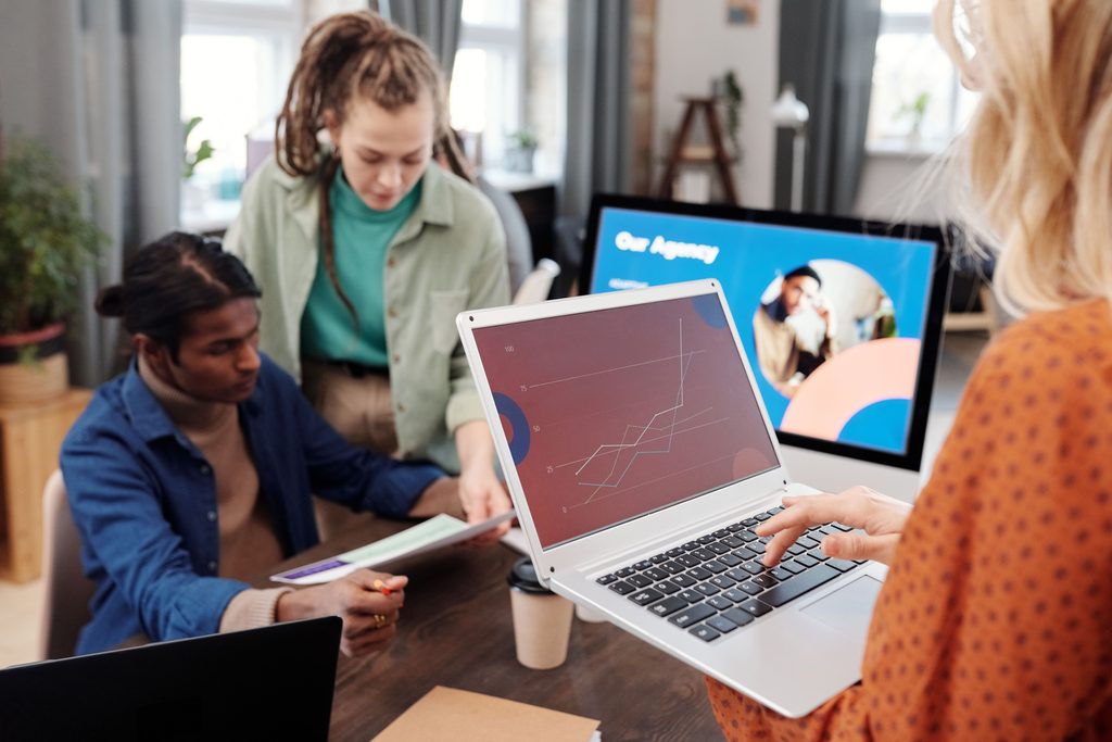Trois personnes autour d’une table de travail, un ordinateur portable affiche une courbe