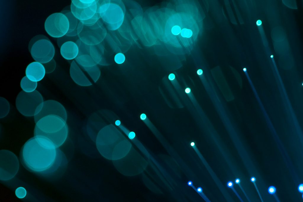 Des fibres optiques turquoise diffusent leur lumière sur un fond noir