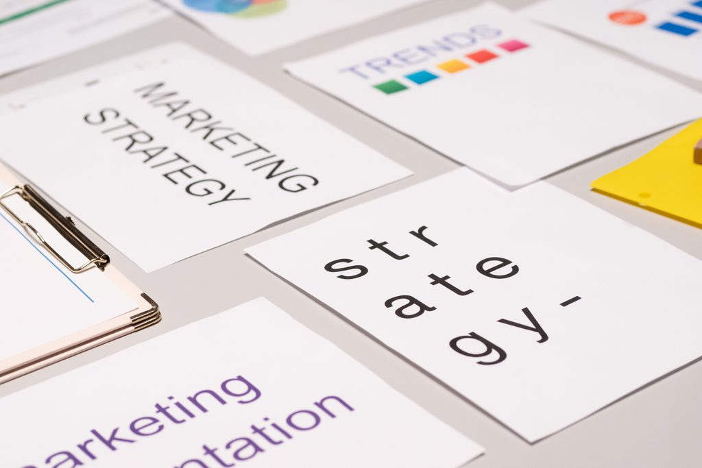 Des fiches imprimées portant les mots « marketing strategy » et « strategy » étalées sur une table