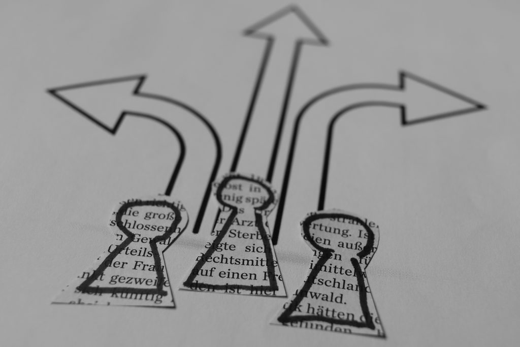 Three arrows cut out of paper heading in different directions