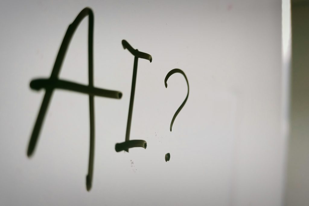 Les lettres « AI » suivies d’un point d’interrogation, écrites au feutre sur un tableau blanc