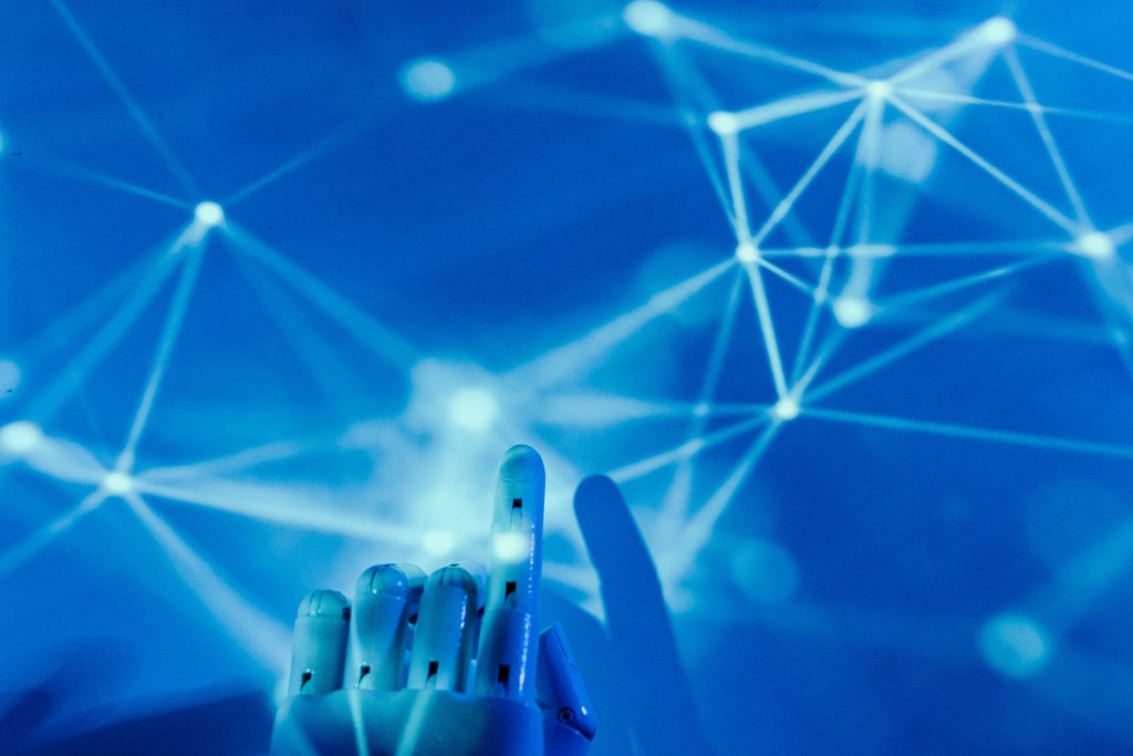 A blue robotic hand reaching towards a network of points joined by lines of light