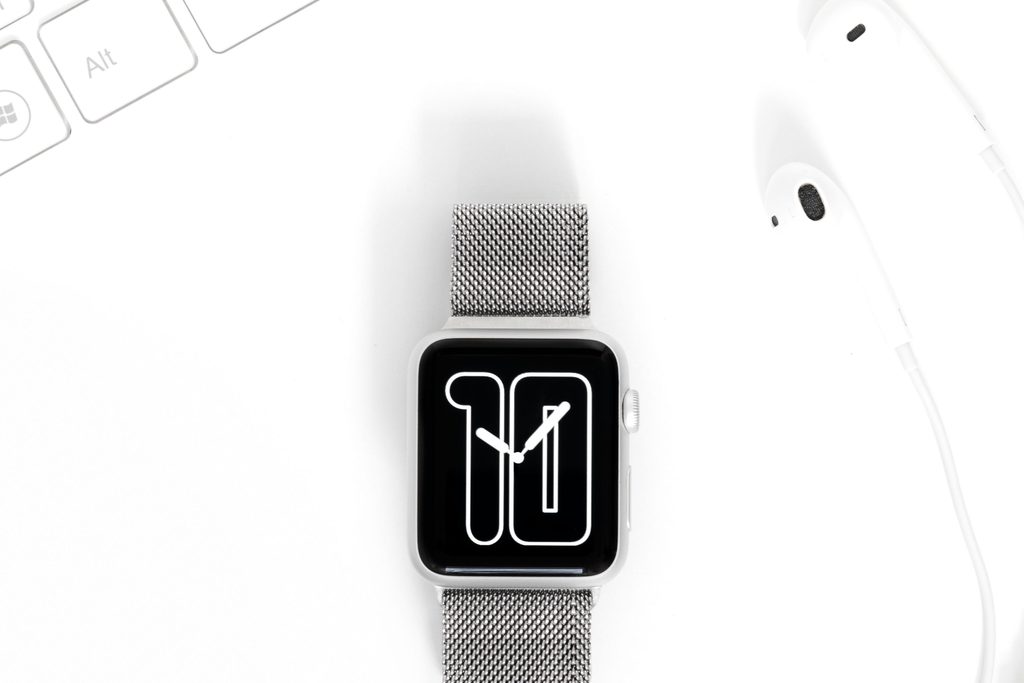Vue de dessus d’une montre connectée, d’écouteurs et d’un clavier blancs sur fond blanc