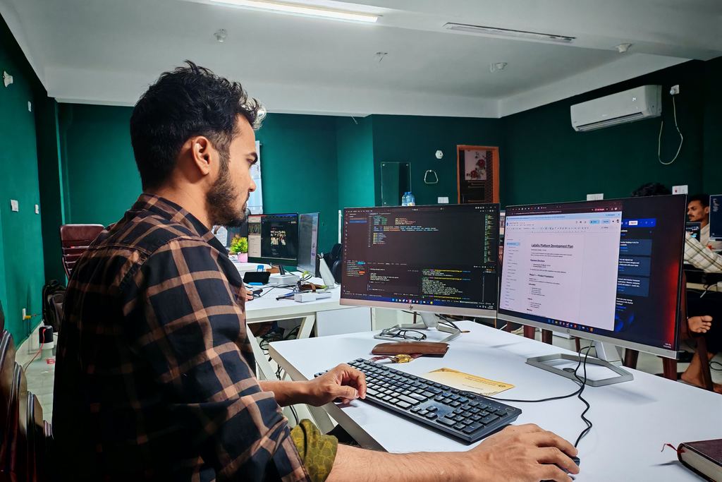 Un développeur travaille devant trois écrans affichant du code et une console d’administration
